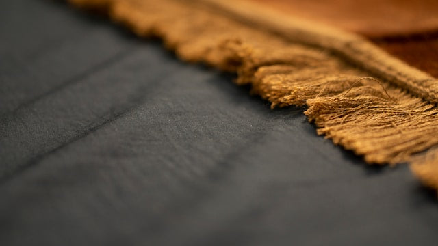 Macro shot of Assomma leather gear featuring handcrafted regenerated cotton crochet edges and textured Minerva Box surface.
